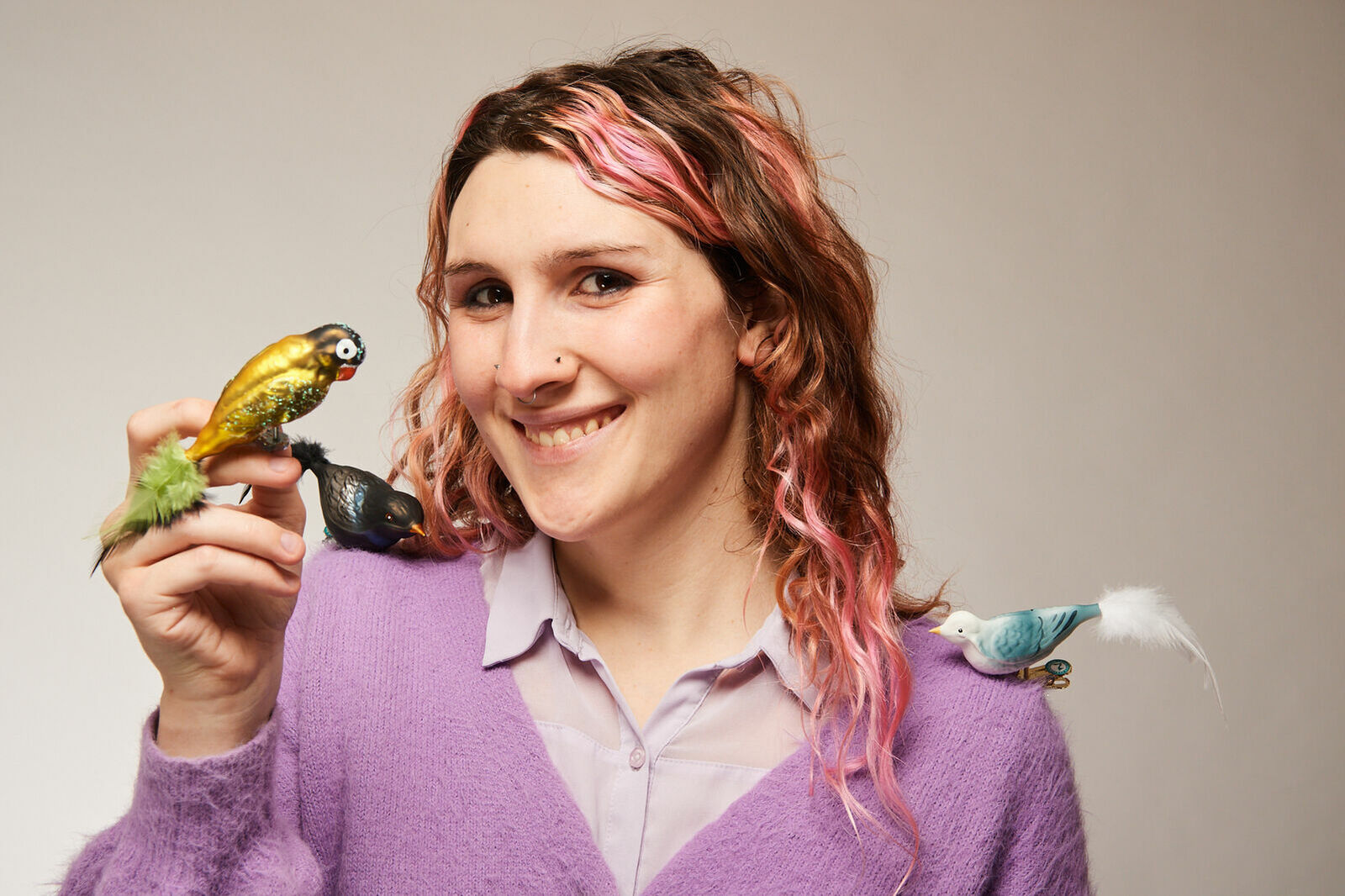 Mitarbeiterin mit drei Glasvögeln, Papagei, Eisvogel und Amsel